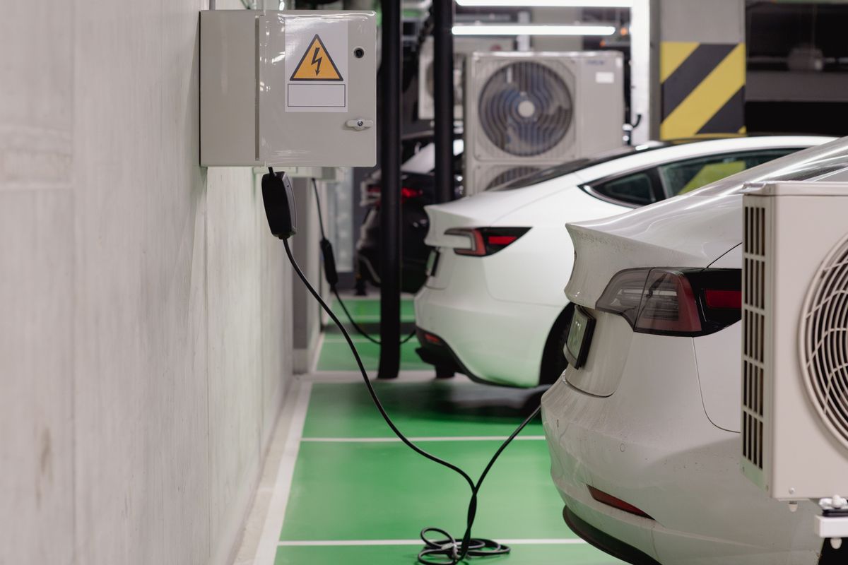 Electric cars charging from wall-mounted AC chargers in a parking garage