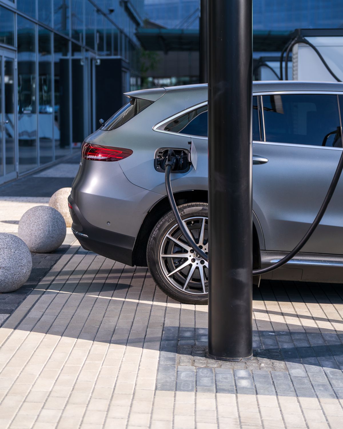 Electric SUV plugged into a fast charger outside a modern building