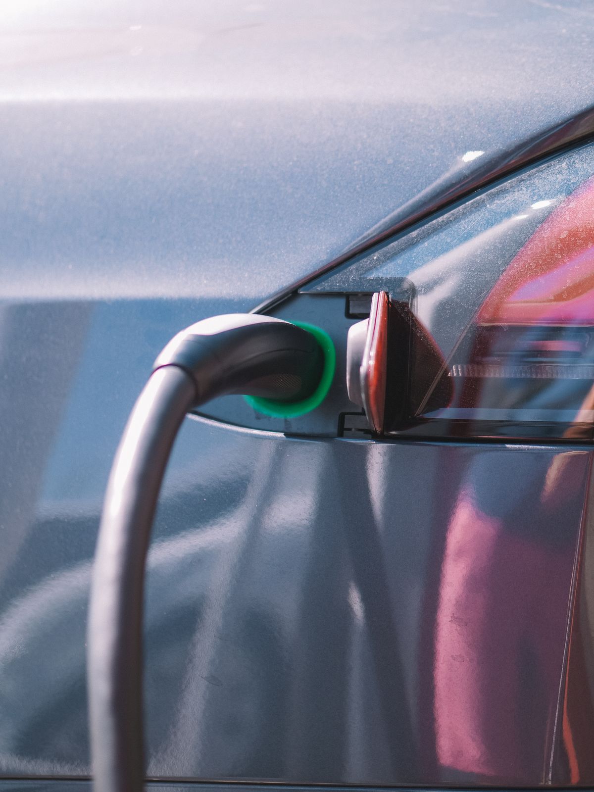 Charging connector plugged into an electric car with a green status light